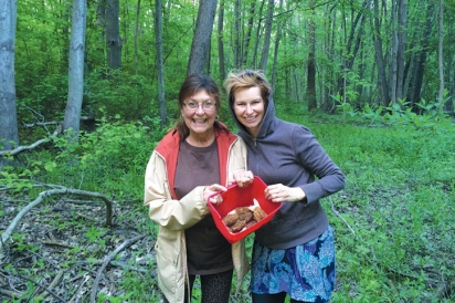 Two women pose in the woods of Goldberry Woods Bed and Breakfast