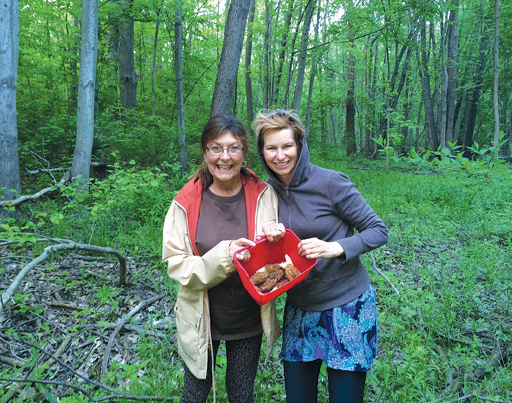 Two women pose in the woods of Goldberry Woods Bed and Breakfast